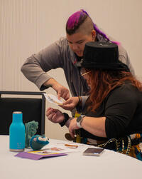 The artist leaning over a workshop participant and explaining the next step.